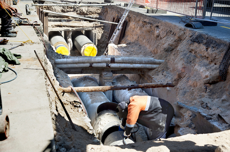 Laying sewer and gas pipes under the ground in a city street. Work welder.の写真素材