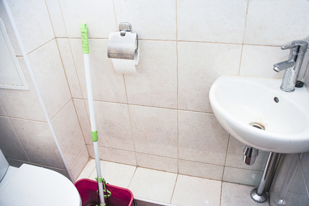 Toilet room with toilet bowl, corner washbasin and hygiene itemsの写真素材