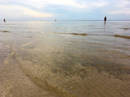 Latvia, Jurmala. An evening swim in the Riga Gulf of the Baltic Sea against the backdrop of a yacht on the horizon.の写真素材
