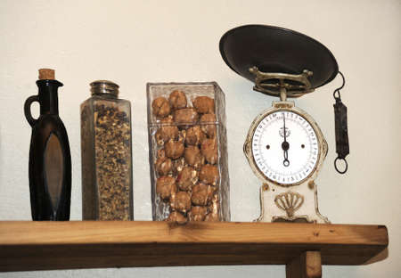 Shelf in the kitchen with antique scales, a bottle for olive oil and dishes with walnuts.の写真素材