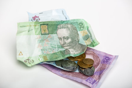 Bruising Ukrainian hryvnia currency and coins on a white background.