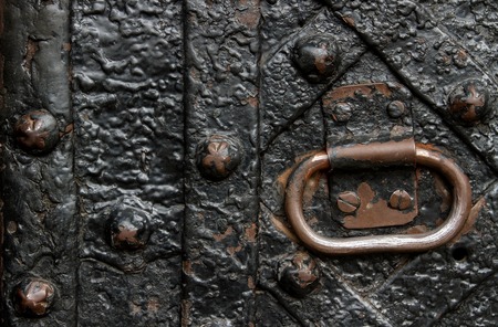 Detail of wrought iron door with a metal handle. bound plates and curly old nailsの写真素材
