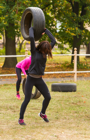 Kyiv, Ukraine - October 08, 2016. CrossFit training, preparation for competition "Race Nation."  Autumn. Girl raises the tire over his head and forcefully throwing her to the ground.のeditorial素材