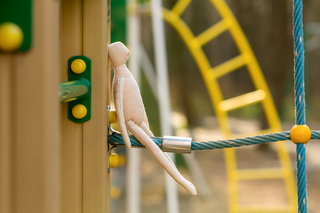 The sewn faceless doll in the profile sits on a blue rope, the construction of a playground.の写真素材