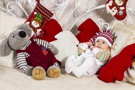 baby in a knitted cap lying on the sofa among pillows and toys on New Year's themeの写真素材