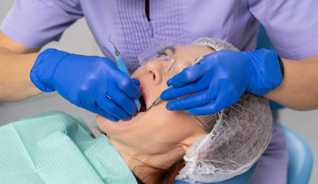 A dentist doctor with a dental mirror and a dental probe examines the oral cavity of a girl patient.
