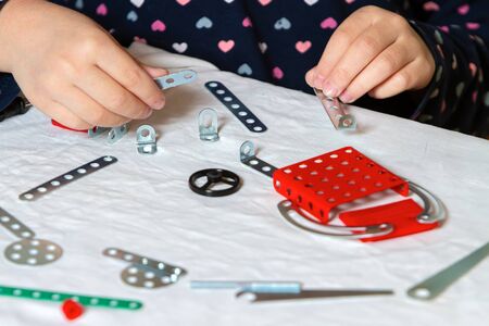 child plays with an iron constructor, collects a robot, hands close-up.の写真素材