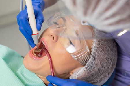 at the dentist's appointment. / Close-up of a girl's patient at the moment when the dentist is using...