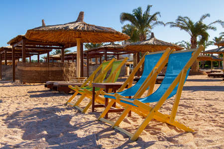 four sun loungers and a table on a deserted empty beach, sun loungers and umbrellas on the shores of the Red Sea, evening, winter Sharm el Sheikh, Egyptの写真素材