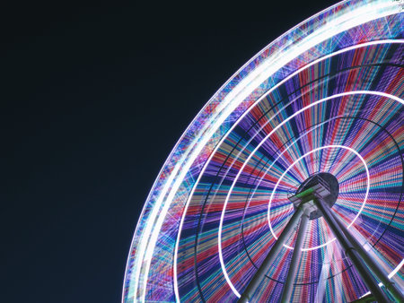 Ferris wheel at night long exposure light lines in a circle on a gradient sky background, copy space