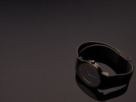Black ladies luxury watch with metal strap mesh on a table gray gradient background
