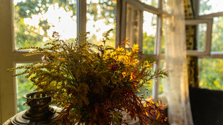 A beautiful vase filled with vibrant flowers is sitting in front of a windowの写真素材