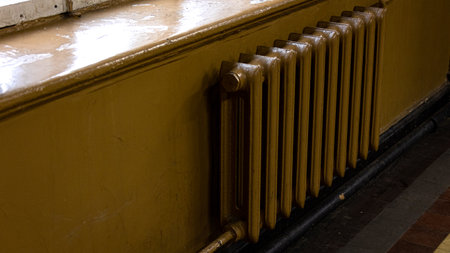 There is a radiator installed on a wall right next to a window sillの写真素材