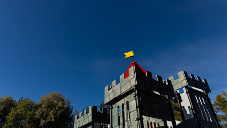 There is a grand castle showcasing a vibrant yellow flag flying atop itの写真素材