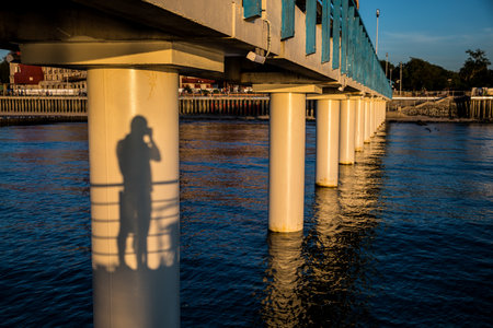 A persons shadow photographing a bridge over waterの写真素材