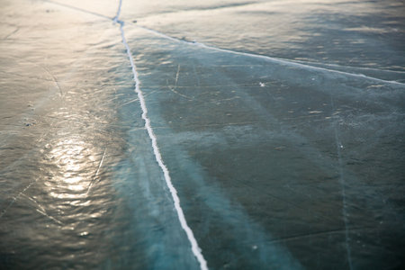 The Ice Surface Features Cracks and Unique Reflections That Create a Captivating Sceneの写真素材