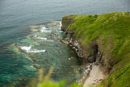 A stunning cliff overlooking the ocean, waves crashing against shoreの写真素材