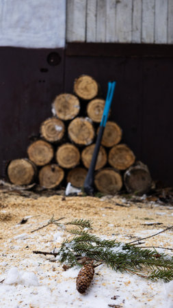 A large pile of logs alongside a shovel resting in the snowの写真素材
