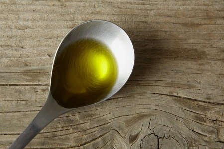 spoon full of olive oil on a wooden tableの写真素材