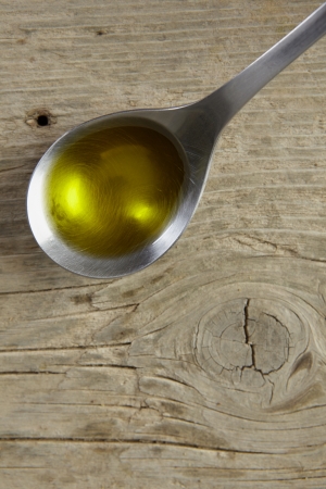 spoon full of olive oil on a wooden tableの写真素材