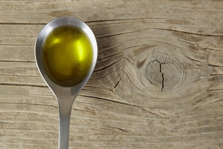 spoon full of olive oil on a wooden tableの写真素材