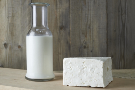 Fresh feta cheese with bottle of milk on a wooden tableの写真素材