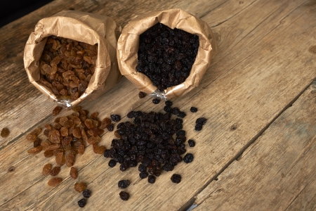 Golden and black raisins in paper bags on a wooden tableの写真素材