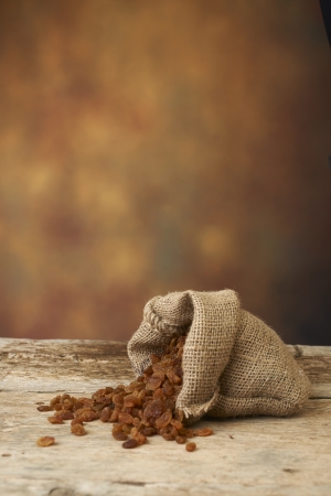 Golden raisins in burlap bag over wooden tableの写真素材