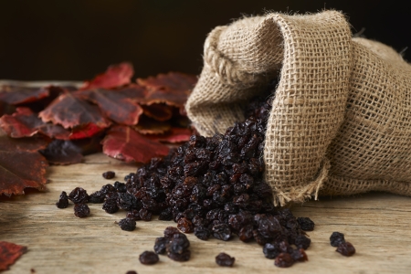Black raisins in burlap bag over wooden tableの写真素材