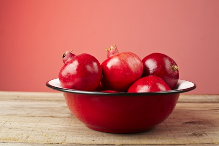 Red pomegranate fruit in a plate on wooden table.の写真素材