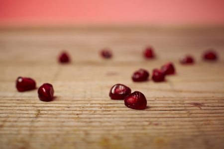 Red pomegranate fruit seeds on a wooden tableの写真素材