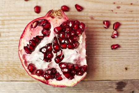 Red pomegranate fruit seeds on a wooden tableの写真素材