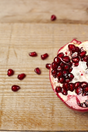 Red pomegranate fruit seeds on a wooden tableの写真素材