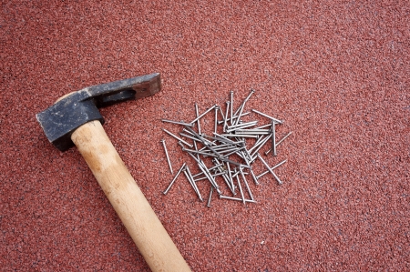Do it yourself, hammer with nails on red roof shinglesの写真素材
