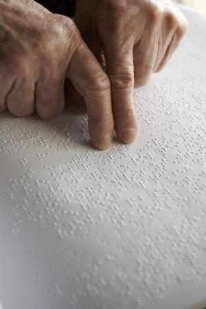 Old womans hands, reading a book with braille languageの写真素材