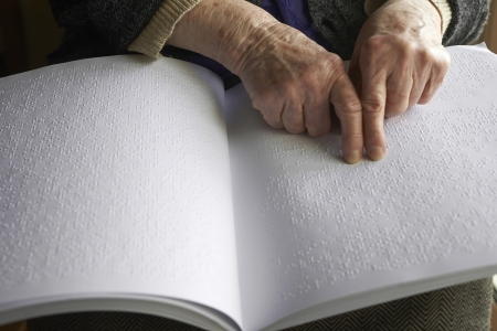 Old womans hands, reading a book with braille languageの写真素材
