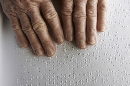 Old womans hands, reading a book with braille languageの写真素材