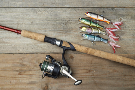 colorful lures with the fishing rod on the wooden pierの写真素材