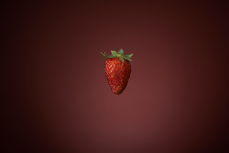 fresh red strawberries in a red bowl on checkered tablecloth, with red backgroundの写真素材