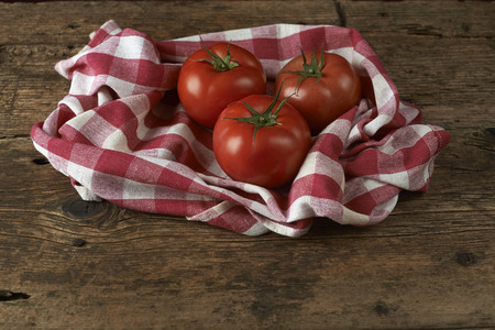 fresh red tomatoes on checkered tablecloth, with red backgroundの写真素材