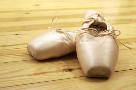 pair of ballet shoes pointes with ribbons on wooden floorの写真素材