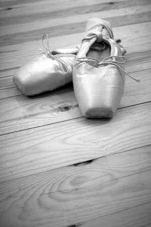 Black and white photo, 
pair of ballet shoes pointes with ribbons on wooden floorの写真素材