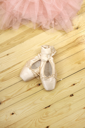 pair of ballet shoes pointes with ribbons on wooden floorの写真素材