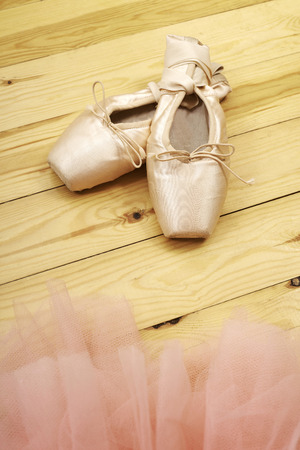 pair of ballet shoes pointes with ribbons on wooden floorの写真素材