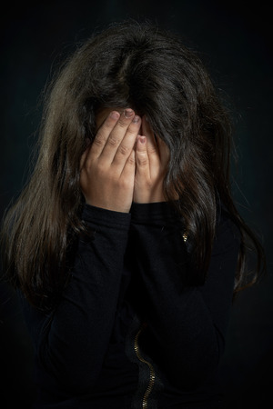 Portrait of a crying girl  She is covering her face の写真素材