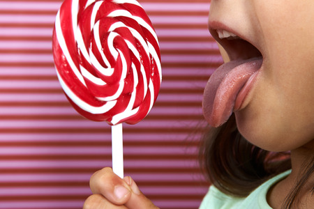girl enjoy licking a large spiral lollipop.の写真素材