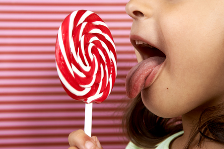 girl enjoy licking a large spiral lollipop.の写真素材