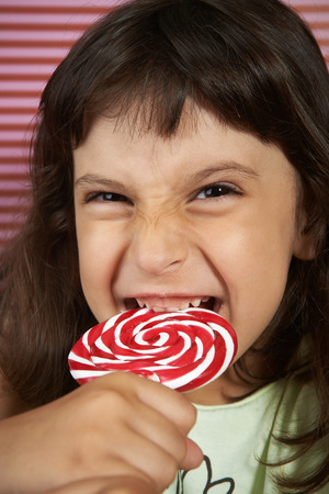 girl biting furiously a large spiral lollipopの写真素材