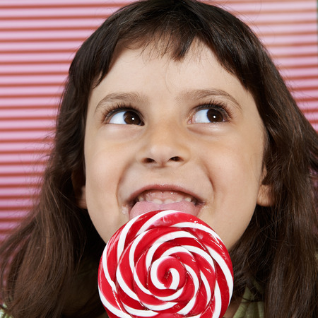girl secretly enjoys a large spiral lollipop.の写真素材
