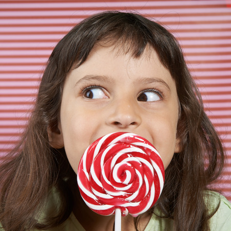 girl secretly enjoys a large spiral lollipop.の写真素材